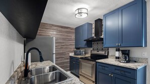Eine moderne Küche mit Edelstahlgeräten, blauen Schränken und einer Granitabdeckung.