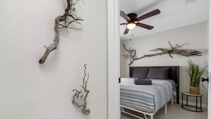 Ein Schlafzimmer mit einem Bett, einem Deckenventilator und Wandzweigen.