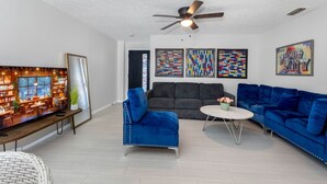 Ein Wohnzimmer mit Sofa, Sesseln, Couchtisch und Fernseher.