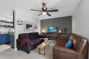 Un salon moderne comprenant un canapé, une table basse, un téléviseur et un ventilateur de plafond.