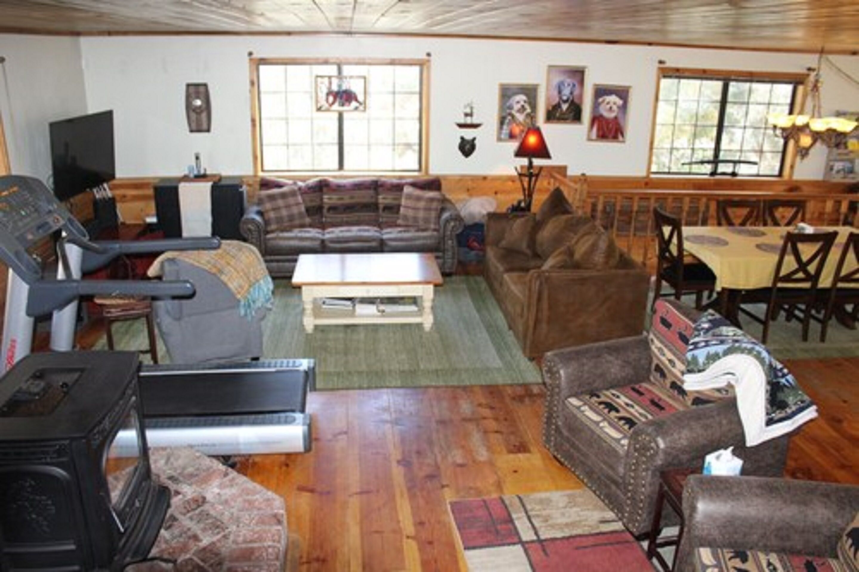 A living room with a treadmill, sofa, and dining area.