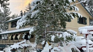 A snow-covered building with a porch and a signboard. - The Old Bear BnB (Pine Mountain Club)