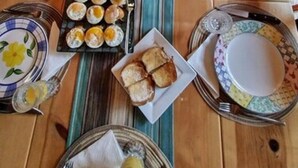 A breakfast table with plates, bowls, and a fruit bowl. - The Old Bear BnB (Pine Mountain Club)