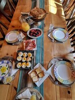 Una mesa de desayuno con platos, tazones y un frutero.