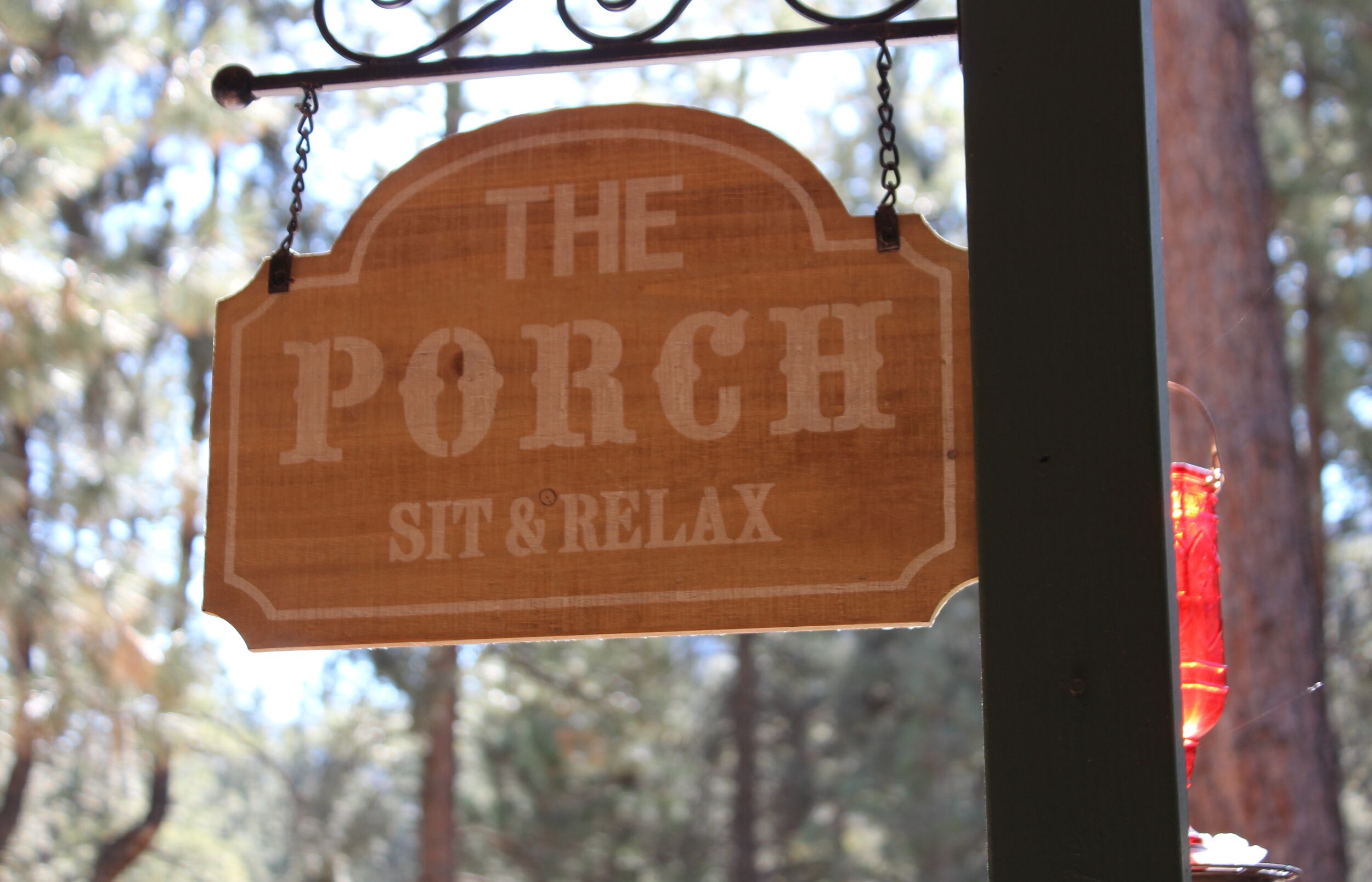 Um letreiro de madeira com o texto 'THE PORCH SIT & RELAX'.