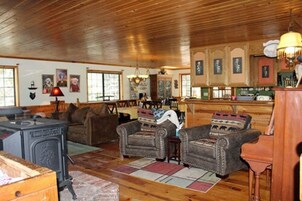 Un salón acogedor con chimenea, pisos de madera y un comedor con una cocina al fondo.