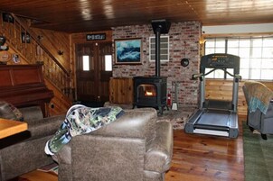 Una sala de estar acogedora con chimenea, cinta de correr y una escalera.
