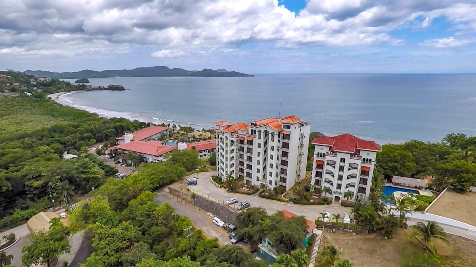 Un hotel moderno con molti piani, una piscina e vista sul mare.