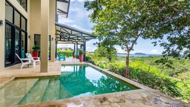 A swimming pool with a view of a lush landscape and distant mountains. - Nostalgic Retro Home on Luxurious Lot with a Private Infinity Pool and Ocean Views (Tempate)
