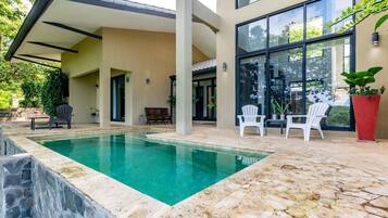 Relax by the clear pool surrounded by a deck and Adirondack chairs.