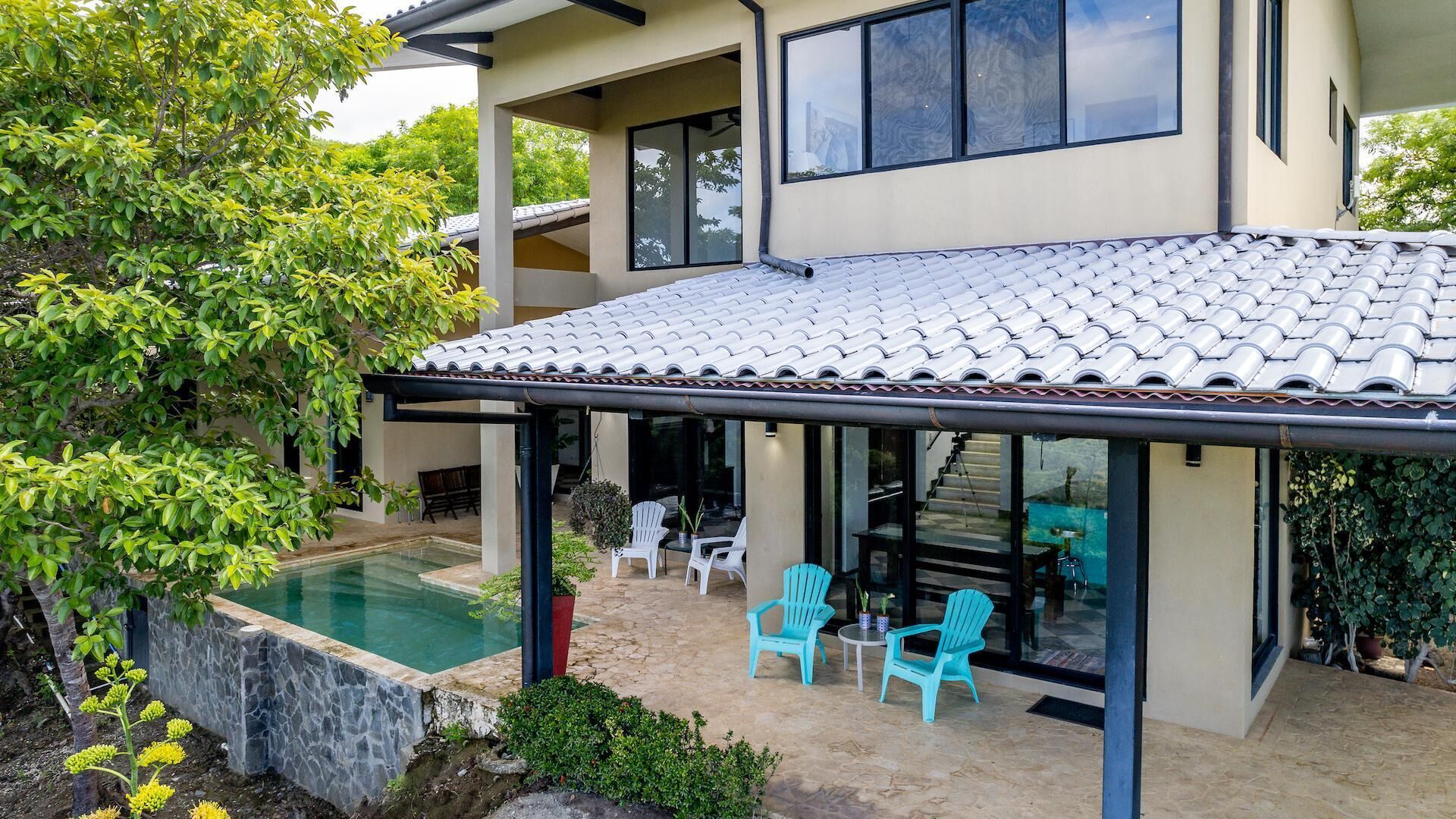 A modern house with a swimming pool, outdoor seating, and a covered patio area.