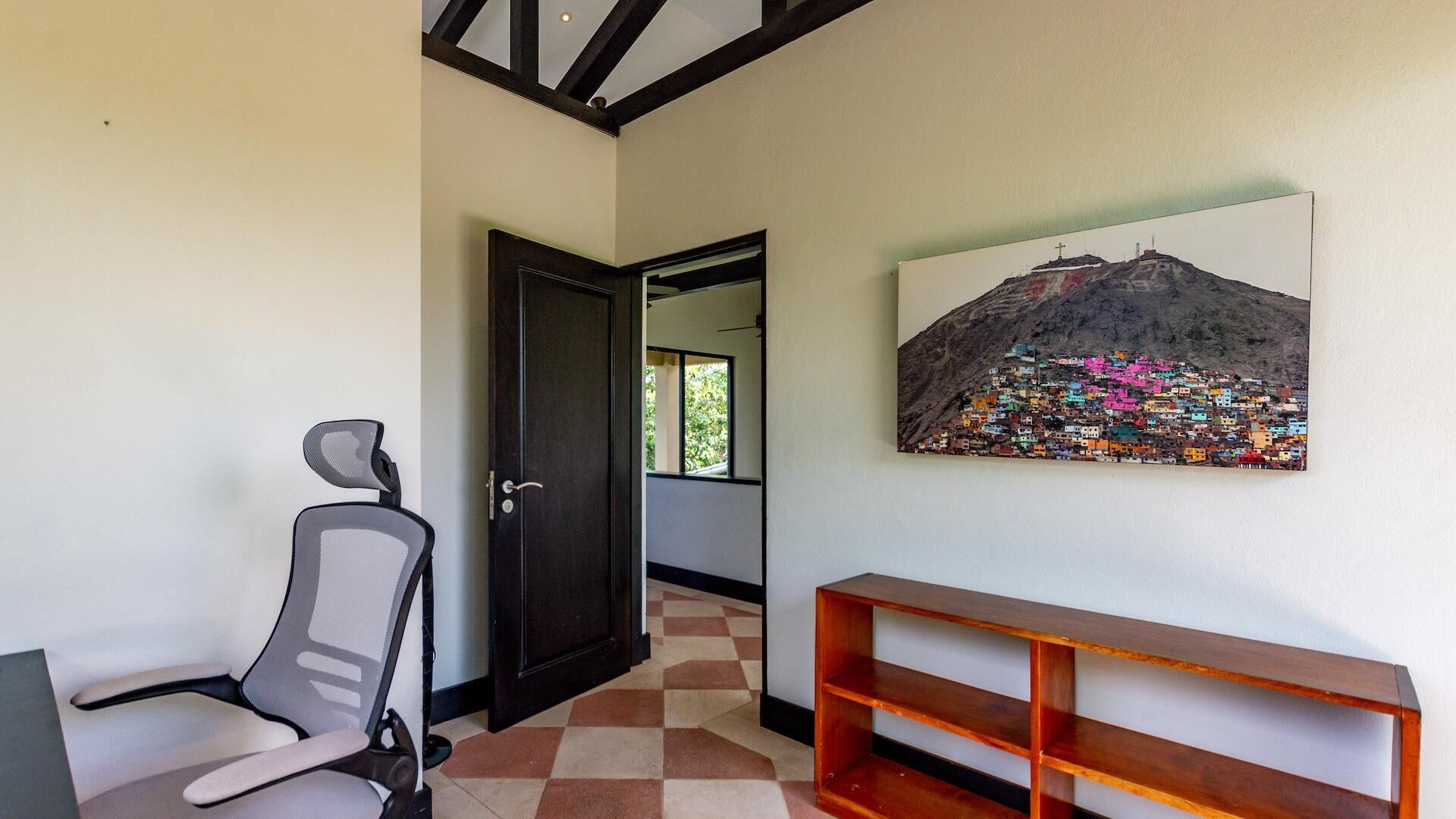 A hallway with a chair, a wooden bench, and a painting of a colorful mountain village.