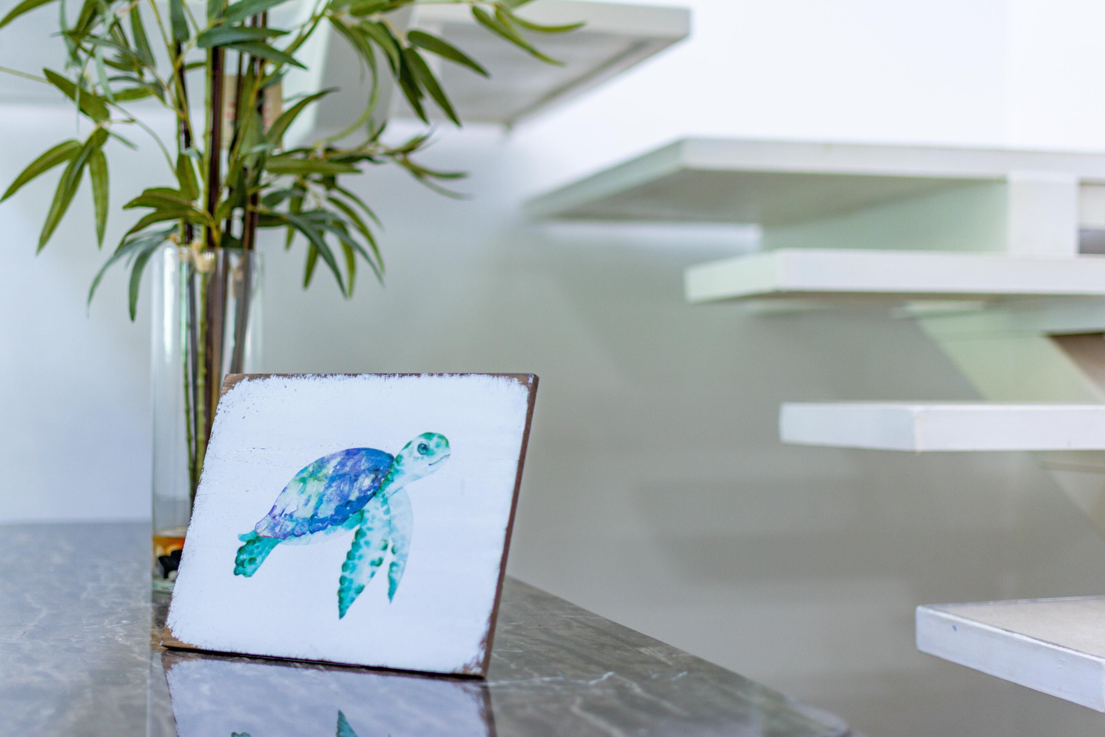 A framed artwork of a sea turtle on a marble surface.