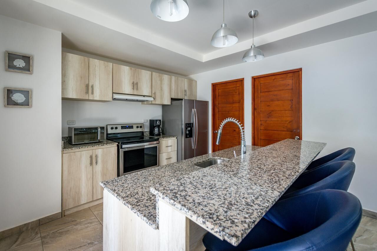 Una cocina moderna con encimeras de granito, electrodomésticos de acero inoxidable y una isla central con asientos.