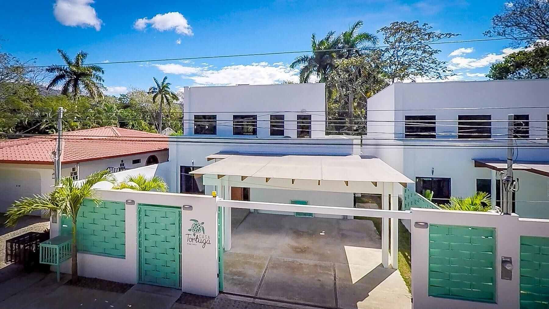 A modern building with a flat roof, a gated entrance, and a sign indicating it is a house.
