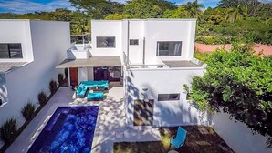 A modern two-story house with a swimming pool, outdoor seating, and a garden. - Ultramodern Townhome with an Inviting Coastal Design and Lush Outdoor Oasis with a Private Pool (Tempate)