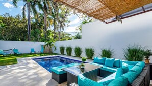 A modern outdoor pool area with a seating arrangement and a pergola overhead. - Ultramodern Townhome with an Inviting Coastal Design and Lush Outdoor Oasis with a Private Pool (Tempate)