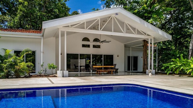 A modern house with a covered patio, a swimming pool, and a dining area. - Modern Home and Guesthouse in a Peaceful Gated Community with a Private Swimming Poo (Cabo Velas)