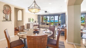 A dining area with a large table, wicker chairs, and a ceiling fan.