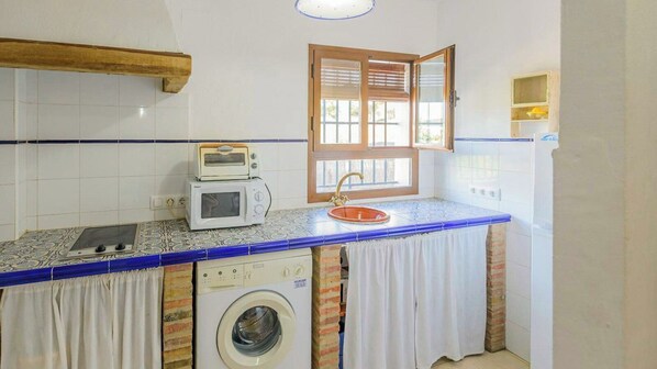 A compact kitchen with a washing machine, a microwave, and a sink. - El Garrotal - El Aceite Almazara El Bosque by Ruralidays (Cádiz)