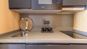 Una cocina moderna con un lavamanos de acero inoxidable, una cesta redonda tejida y dos tazas negras sobre una bandeja.