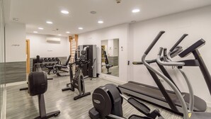 Un gimnasio moderno con máquinas de cardio, estaciones de pesas y un muro de espejos.