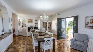 Een ruime woonkamer met een eettafel, witte banken en een gestreept fauteuil.
