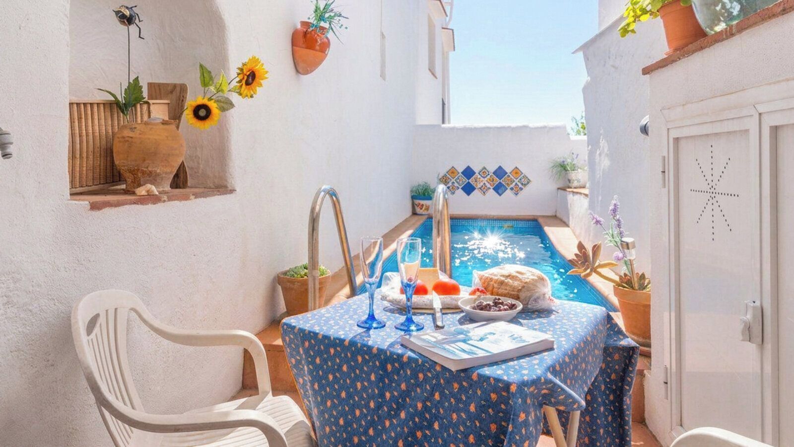 Un petit espace extérieur aménagé pour prendre les repas, avec une table pour deux, une piscine et des plantes en pot.