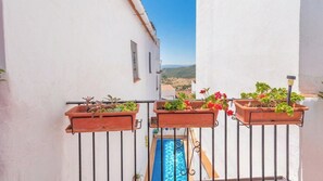A balcony with terracotta planters containing plants and flowers, a pool, and a view of the landscape. - Casa Chantal Gaucín by Ruralidays (Málaga)