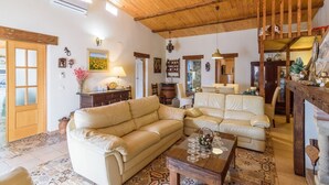 A cozy living room with a wooden ceiling, a beige sectional sofa, a wooden coffee table, and a rustic fireplace.