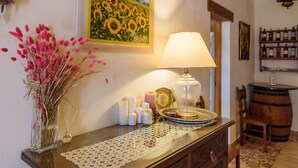 A well-lit room with a table displaying candles, a lamp, and a vase of flowers.