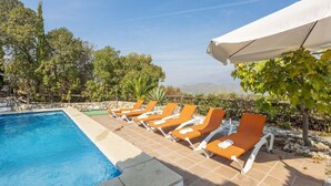A poolside area with lounge chairs and a white umbrella.