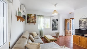 A living room with a sofa set, a television, and artwork on the walls.
