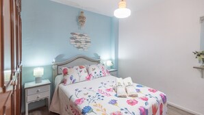 Een slaapkamer met een bed, twee nachtkastjes, een wanddecoratie en een kroonluchter.