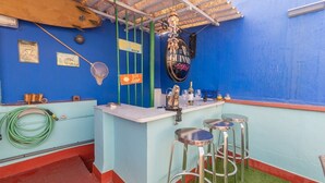 Een bar met een blauwe muur, een Guinness-bord en een toog met barkrukken.