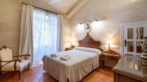 Quarto de hotel com cama, uma cadeira, mesa de cabeceira e armário.