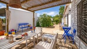 An outdoor patio with a table set for two, a blue bench, and a wicker canopy. - Finca Los Arcos - Heredad de los Capuchinos Ronda by Ruralidays (Málaga)