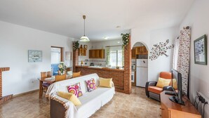 A cozy living room with a sofa, a TV, and a dining area with a table and chairs. - Villa Tranquila Nerja by Ruralidays (Málaga)