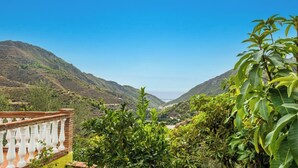 A mountainous landscape with a clear sky, a bridge in the distance, and lush greenery in the foreground. - Villa Tranquila Nerja by Ruralidays (Málaga)