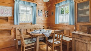 A cozy wooden cabin with a dining table set for four, surrounded by wooden chairs. - Alpin Cabin in Klippitz (Klippitztörl)