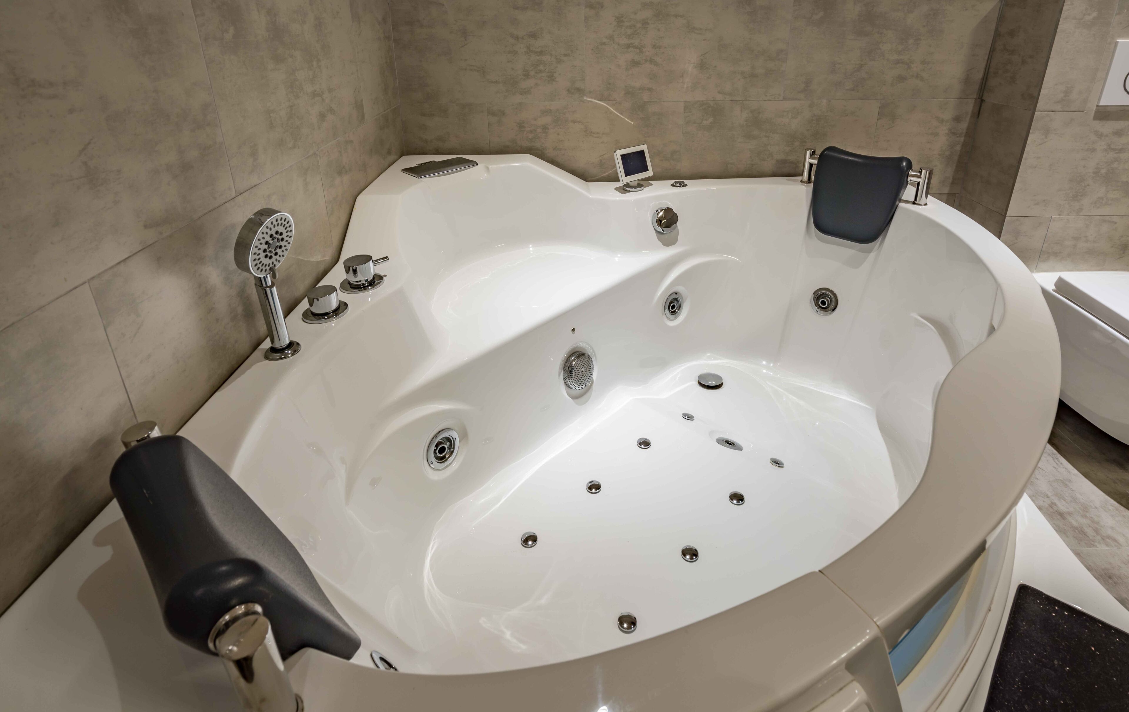 A modern bathroom with a freestanding bathtub, a handheld showerhead, and a small control panel.