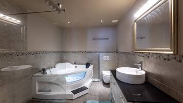Un baño moderno con una bañera independiente, un tocador con lavabo y un espejo grande.