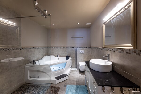 Un baño moderno con una bañera independiente, un tocador con lavabo y un espejo grande.