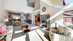 Uma sala de estar espaçosa com lareira, área de jantar e cozinha.
