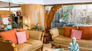 A living room with two sofas, a coffee table, and a Buddha statue. - New Waikiki Boutique Condo 1.5 blocks to the sands of Waikiki Beach!  (Honolulu)