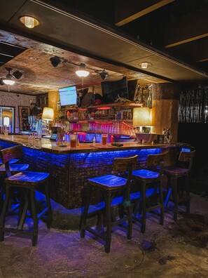A bar with a blue-lit bar counter and wooden stools.