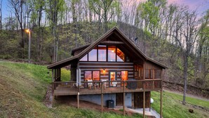 Una cabaña con balcón, ventanas amplias y chimenea.