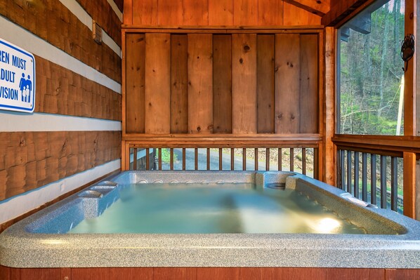 A wooden cabin with a hot tub and a sign indicating it is for adults only.