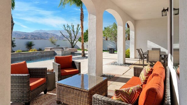 An outdoor patio area with wicker furniture, a pool, and a view of mountains.