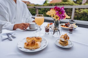 A table with croissants, a glass of orange juice, and a vase of flowers.